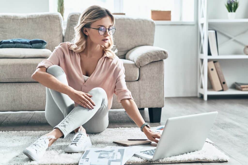 Woman sitting on the floor with a silver laptop working on a Why Use WordPress blog
