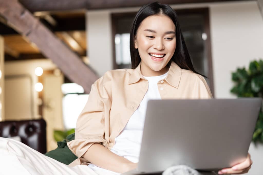 Woman smiling while using a laptop (Posts vs pages WordPress)