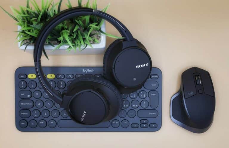 Bluetooth headphones on top of a keyboard with a mouse beside them